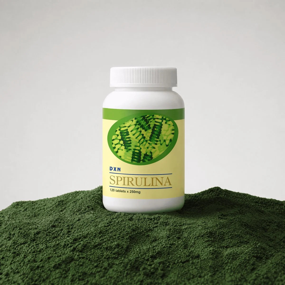 DXN Spirulina 120 tablets bottle on a mound of green spirulina powder